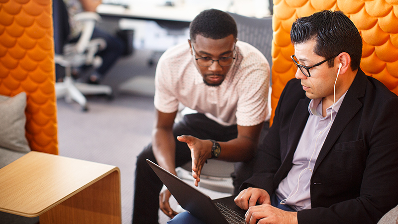 Oportunidades de empleo en Visa Two seated men discussing laptop display.