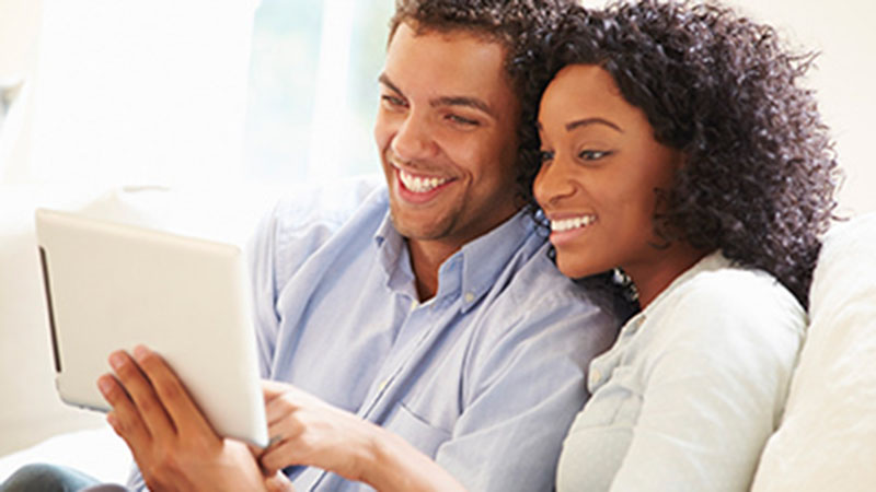 pareja sonriendo frente a una tablet