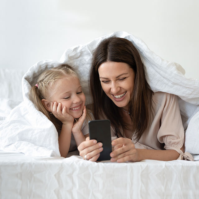 Madre e hija sonriendo mirando el teléfono móvil