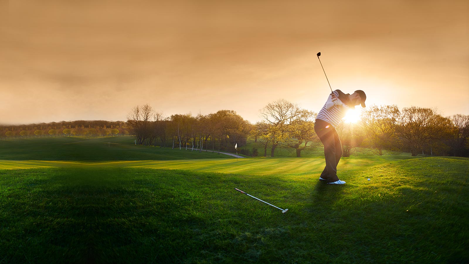 Hombre jugando al golf al atardecer