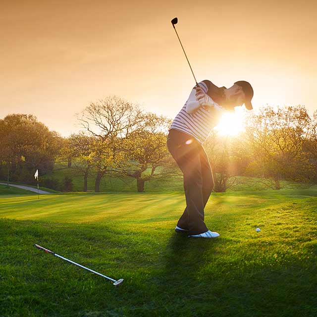Hombre jugando al golf al atardecer