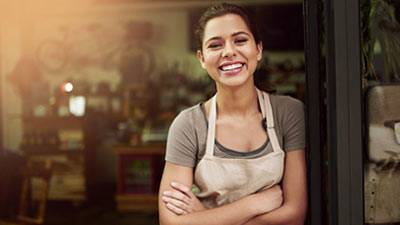 Mujer sonriente en la puerta de su comercio