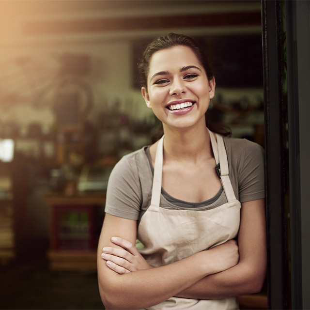 Mujer sonriente en la entrada a su comercio